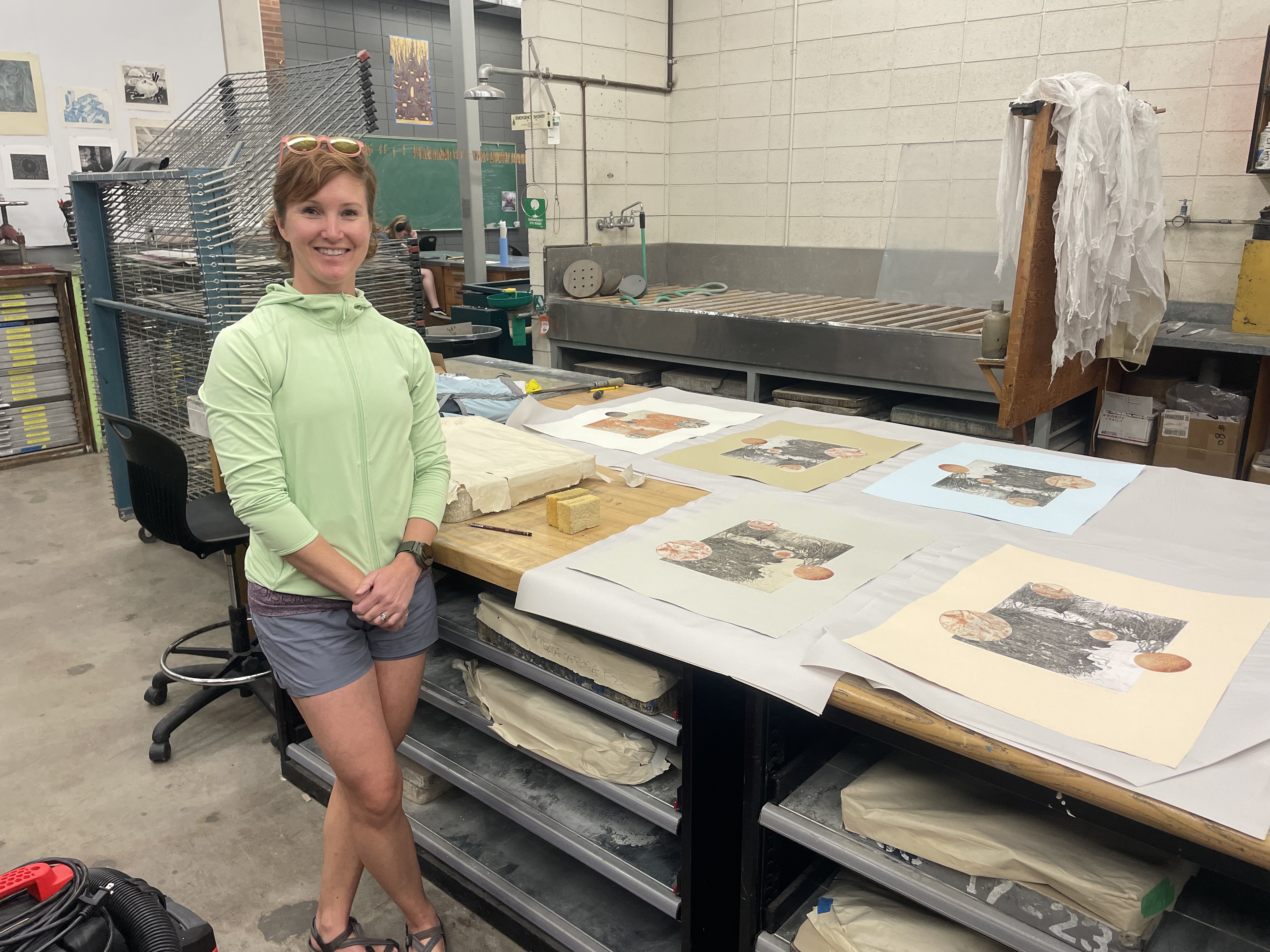 Student artist Rachel Ingle stands next to her prints at MSU