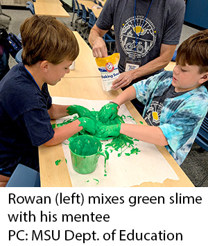 Rowan mixes green slime with his mentee. Photo credit: MSU Department of Education