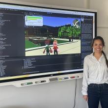 Graduate student Tasha Stryker stands next to a development version of the online Crash Course game