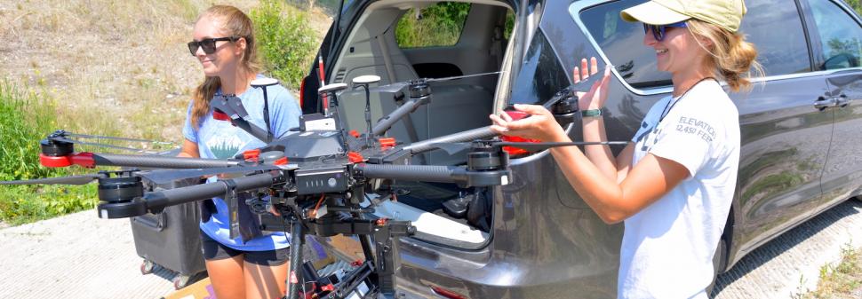 CREWS undergraduate students Maddie Torrey, left, and Shannon Hamp, right, begin the process of packing up the drone after a flight on the Upper Clark Fork River in July 2021.