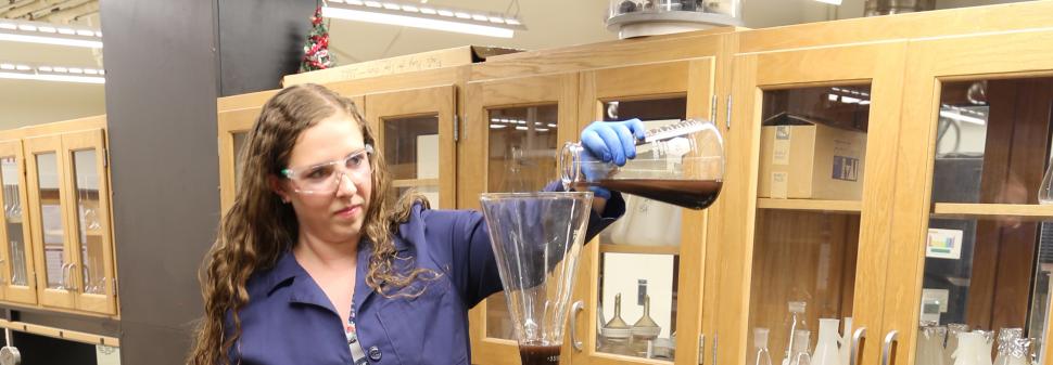 Teagan Leitzke, a Ph.D. student at Montana Tech, pours a slurry of magnetite and water into the continuous flow metal recovery system. The slurry flows through the static mixer column to a magnet, where the magnetite is collected, and water continues to flow out of the system. Photo credit: Amanda Badovinac