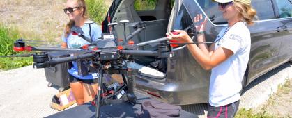 CREWS undergraduate students Maddie Torrey, left, and Shannon Hamp, right, begin the process of packing up the drone after a flight on the Upper Clark Fork River in July 2021.  