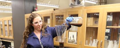 Teagan Leitzke, a Ph.D. student at Montana Tech, pours a slurry of magnetite and water into the continuous flow metal recovery system. The slurry flows through the static mixer column to a magnet, where the magnetite is collected, and water continues to flow out of the system. Photo credit: Amanda Badovinac