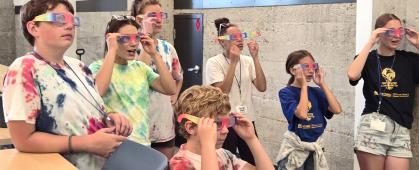 Camp participants use prismatic glasses to view different wavelengths of laser light