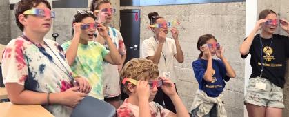 Camp participants use prismatic glasses to view different wavelengths of laser light