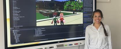 Graduate student Tasha Stryker stands next to a development version of the online Crash Course game